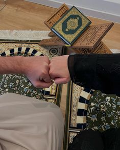 two people holding hands over a rug on the floor