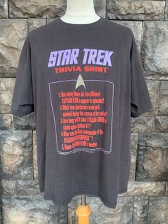 a star trek trivia shirt hanging on a mannequin stand in front of a stone wall