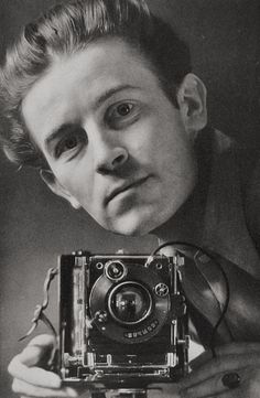 a black and white photo of a man taking a selfie with an old camera