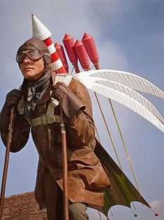 a man dressed in costume holding two red and white kites on top of his head