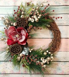 a wreath with flowers and pine cones hanging on a wall