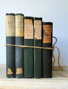 four old books are tied together on a shelf