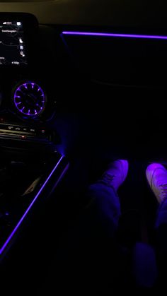 someone is sitting in the car with their feet on the steering wheel, and there are purple lights behind them