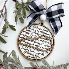 a wooden ornament hanging from a tree with a ribbon around it's neck