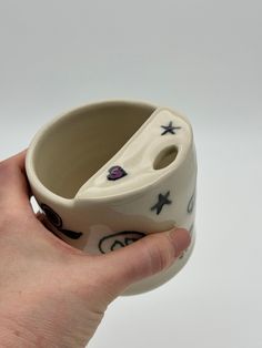 a hand holding a ceramic cup with designs on it