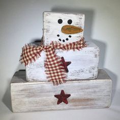 a wooden block with a snowman made out of wood and plaid fabric on top