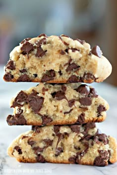 three chocolate chip cookies stacked on top of each other in front of a white marble counter