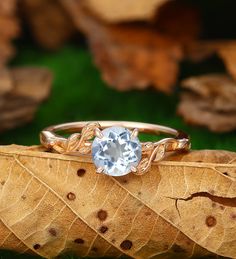 an engagement ring with a blue topaz surrounded by leaves