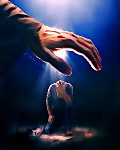 a person kneeling down in front of a hand reaching for the light from above them