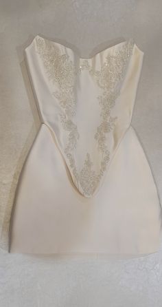 the back of a white wedding dress with gold lace on it's neckline