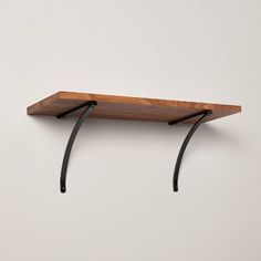 a wooden shelf with two black metal brackets