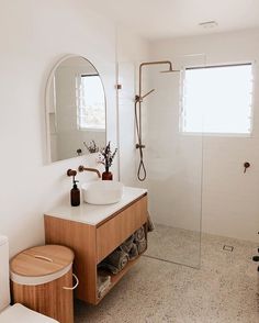 a bathroom with a sink, mirror and shower stall in the corner next to a toilet