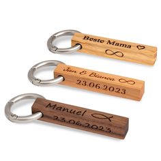 three personalized wooden keychains with metal rings on each one and the names of two