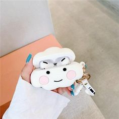 a hand holding a cell phone case with a cartoon character on the front and an airpods attached to it