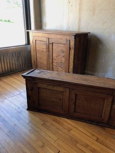 an old wooden bench sitting on top of a hard wood floor next to a window