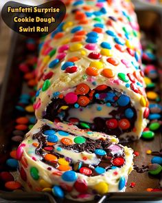 a cake roll covered in candy and sprinkles on a baking sheet with the words funfetti surprise cookie dough swirl roll