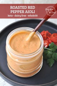 a jar of roasted red pepper garlic aioli on a plate with tomatoes and cilantro