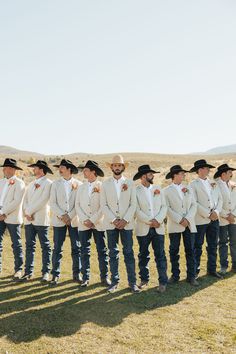 a group of men standing next to each other on top of a grass covered field