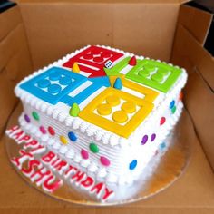 a birthday cake in the shape of a cube with numbers and letters on it, sitting inside a cardboard box