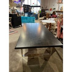 a black table sitting in the middle of a room with chairs and tables behind it