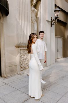 a woman in a white dress standing next to a man