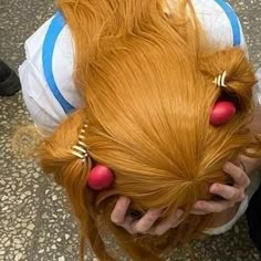 a woman with long red hair has her hands on her head and is wearing gold ear rings