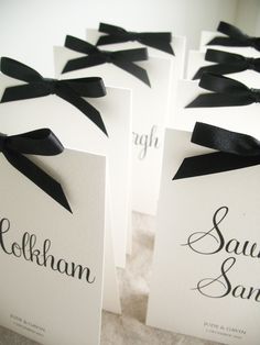 black and white place cards with bows on them