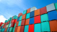 an airplane flying over a large stack of shipping containers