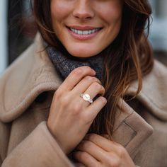 a smiling woman wearing a ring and coat