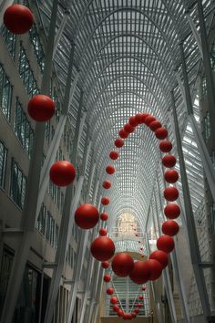 an indoor walkway with red balls hanging from the ceiling