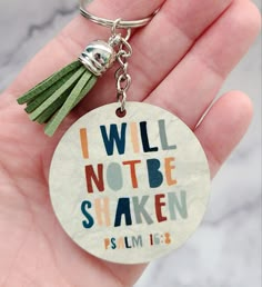 a hand holding a keychain with the words i will not be shaken on it