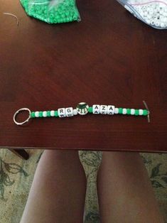 a pair of legs sitting on top of a table next to a green and white beaded bracelet