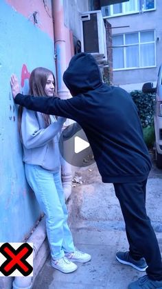 a man and woman leaning against a wall