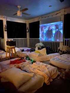 a room filled with lots of unmade beds in front of a projection screen on the wall