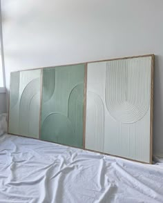 three panels are on the wall above a bed