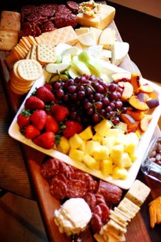 an assortment of cheeses, fruit and crackers on a table