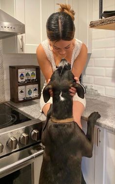 a woman is petting her dog in the kitchen