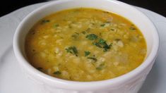 a white bowl filled with soup and garnished with parsley on the side