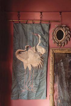 a wall hanging next to a mirror with a painting on it and a bird in the middle