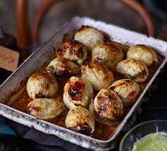 a pan filled with food sitting on top of a table next to a bowl of sauce