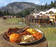 a plate full of food sitting on top of a wooden table in front of horses