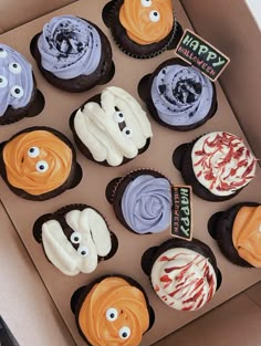 a box filled with lots of cupcakes covered in frosting and decorated like characters