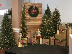 christmas trees and presents are on display in front of a wooden sign that says peace