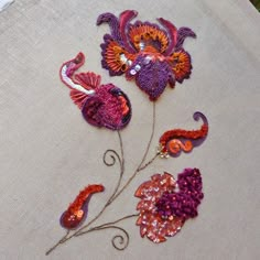 two flowers on a piece of cloth with bead work in the middle, and one flower that has been sewn onto