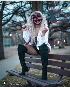 a woman sitting on top of a wooden bench wearing a mask and holding an ax