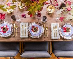 the table is set with plates, silverware and autumn leaves on top of it