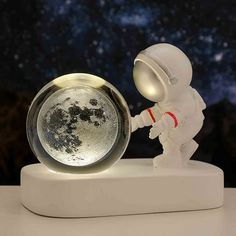 an astronaut figurine holding the moon in his hand