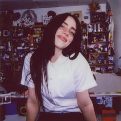 a woman with long hair sitting in front of a computer desk and looking at the camera