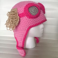 a crocheted pink hat with leaves on the brim and ear flaps