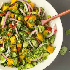 a white bowl filled with chopped vegetables and veggies next to a wooden spoon